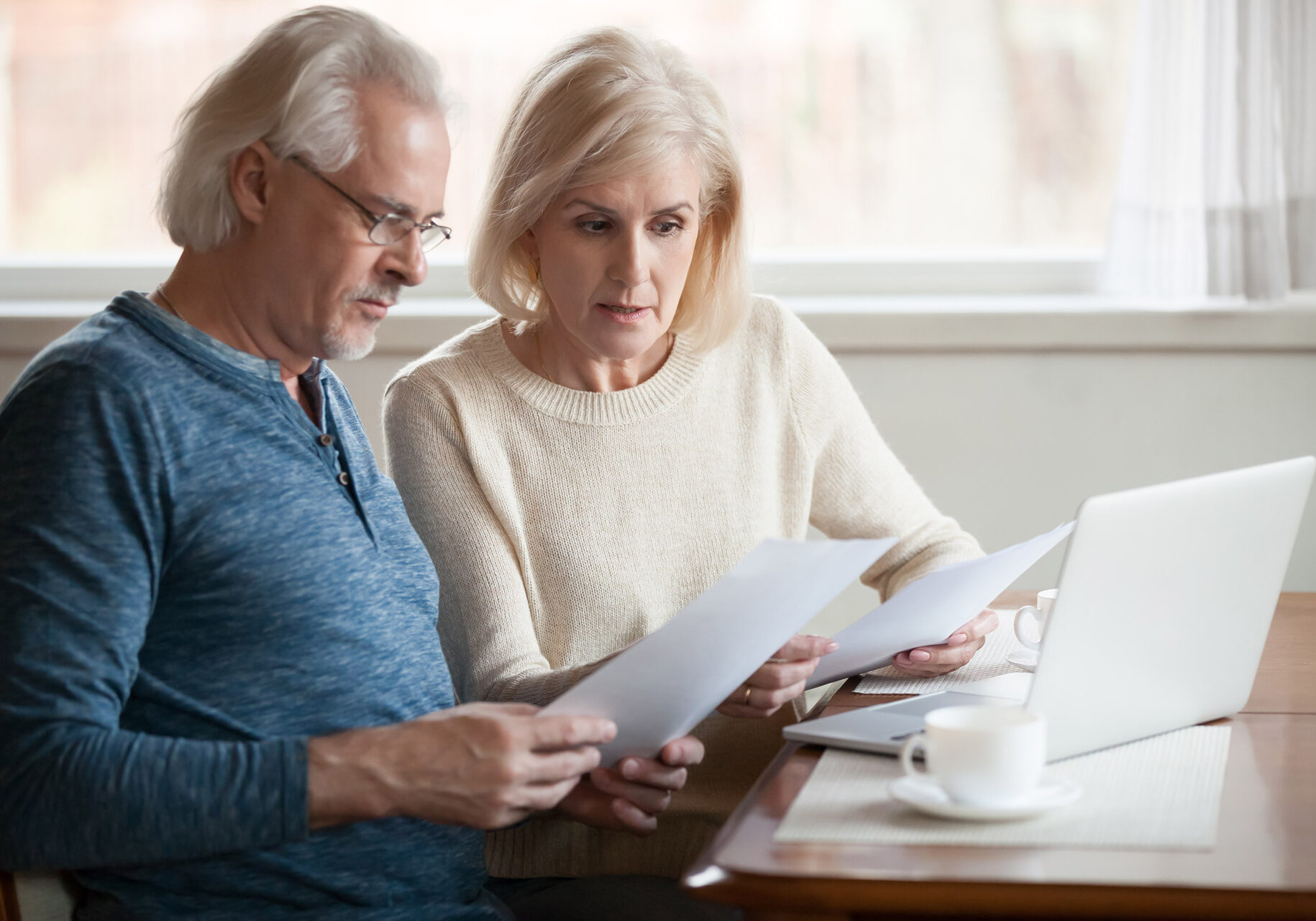 Serious worried senior couple calculating bills to pay