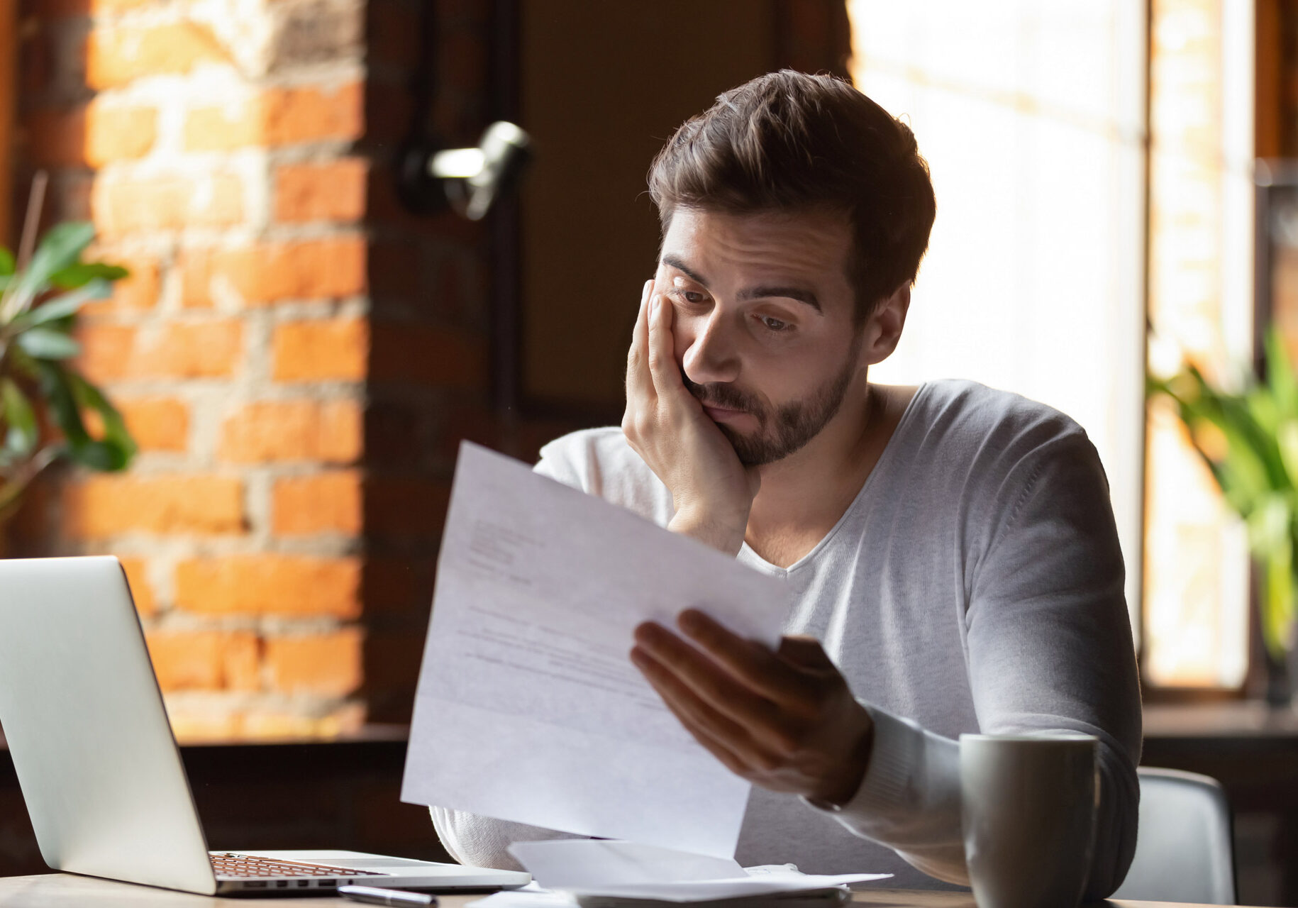 Confused frustrated young man reading letter